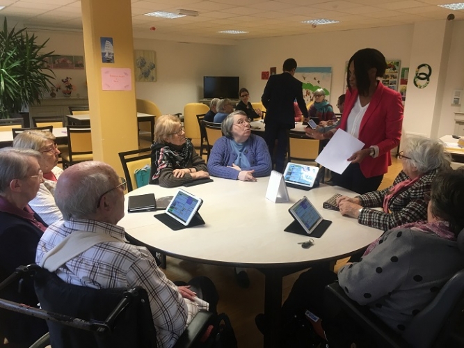 Sept seniors de la résidence « Le Square des âges », assis autour d'une table ronde, en train d'écouter la formatrice Ardoiz.
