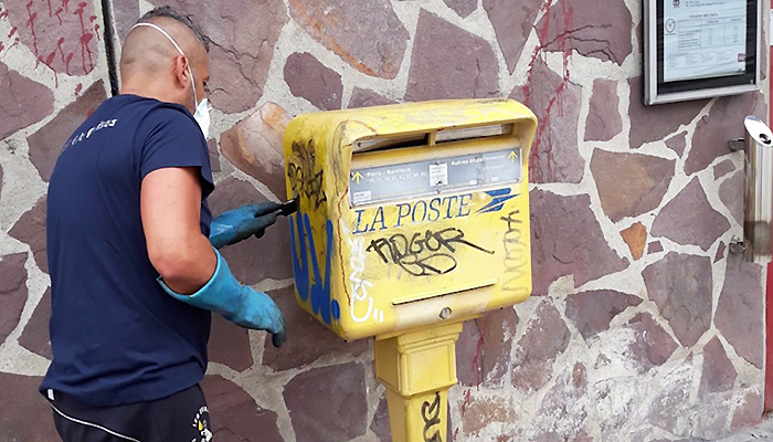Un salarié de l'Association des Paralysés de France nettoyant une boîte aux lettres de rue.