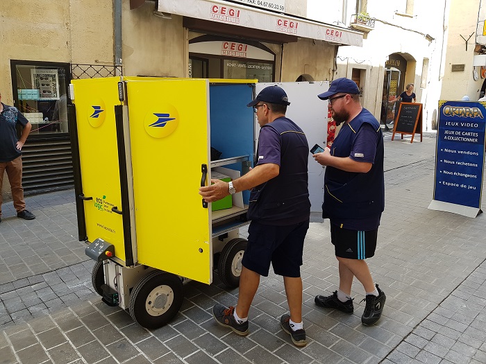 Deux facteurs devant le chariot suiveur : jusqu'à 150 kg de colis.