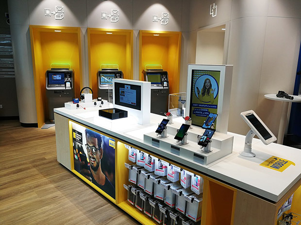Photo de la première zone de services : un présentoir avec des smartphones au premier plan et des automates au second plan.
